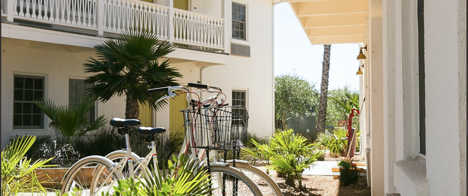 two bikes with baskets parked on a sidewalk outside a resort building
