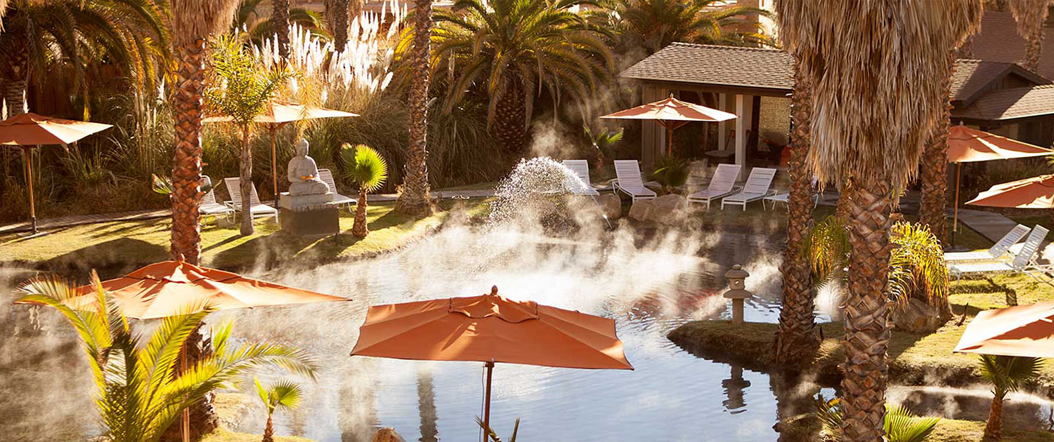 Heated pool with white lounge chairs and orange umbrellas