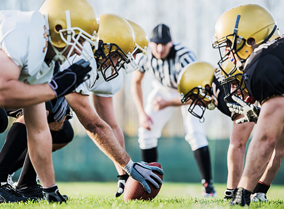 Football players ready to start game with referee in the background