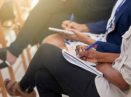 Close up of people writing on notebooks on their lap