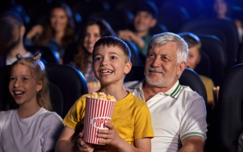 children watching a movie with grandfather and eating popcorn