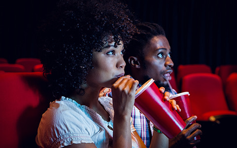a couple watching a movie in the cinema drinking a soda