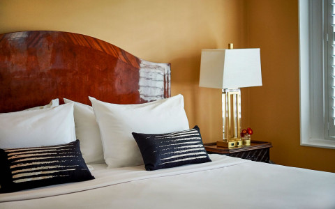 white bed with black pillow details and white lamp