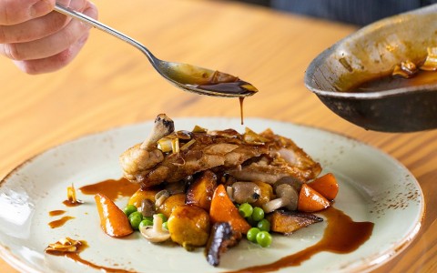 chef drizzling sauce on plate