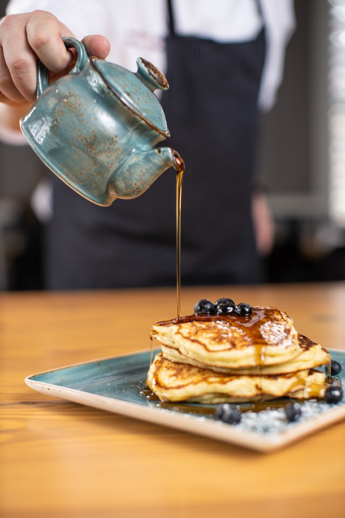 chef pouring syrup on pancakes 