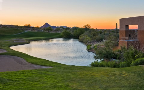 pond next to hotel building and golf course during sun down