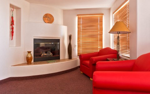 hotel living room with bright red sofa chairs in front of fireplace