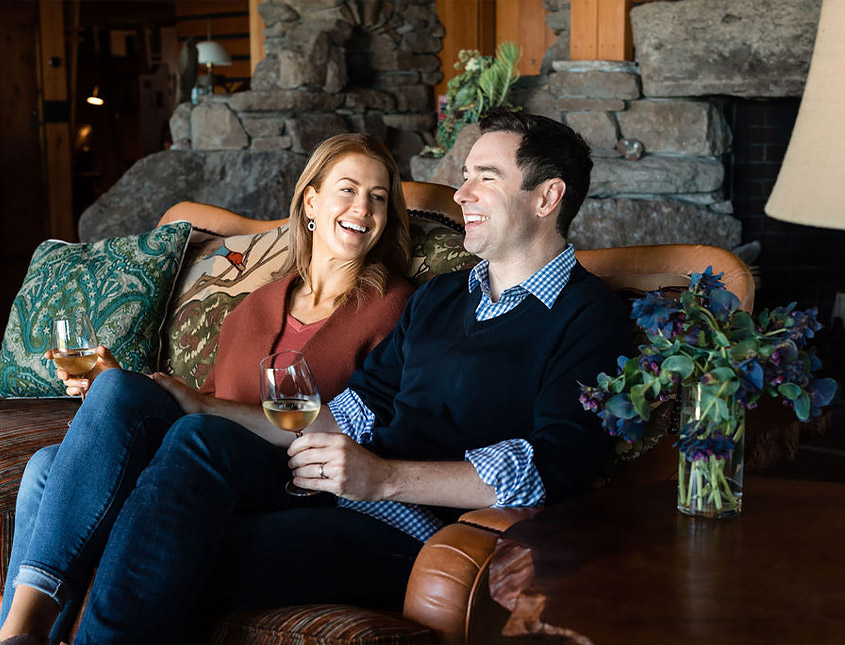man and woman sitting on a couch drinking wine