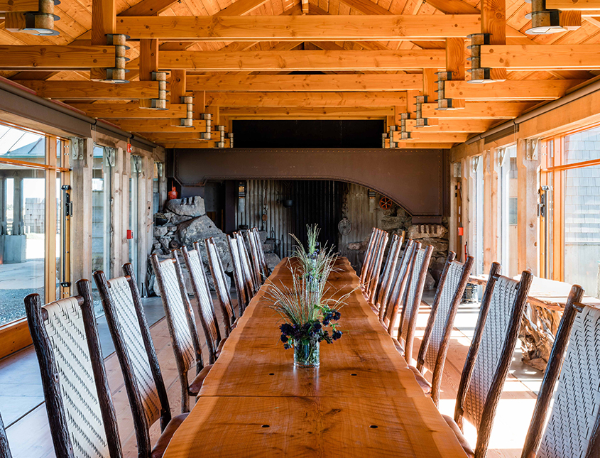 long wood table with green plants and wood beams on ceiling