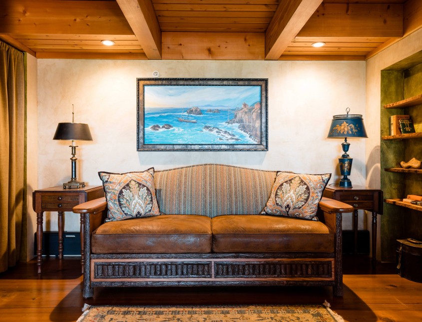 brown leather couch next to two side tables and a painting on the wall