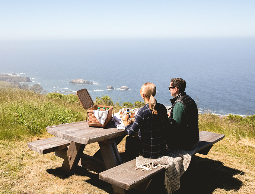 man and woman having a picnic at a picnic overlooking the ocean water from cliffs