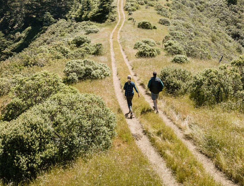 couples walking on a gravel path in an open field