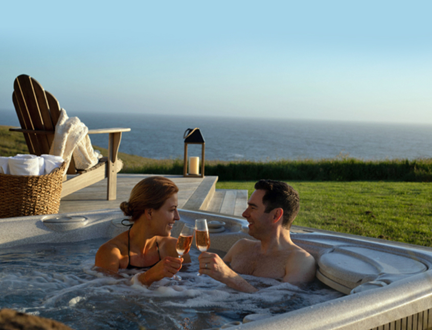 couple in hot tub with view of the ocean drinking Champagne