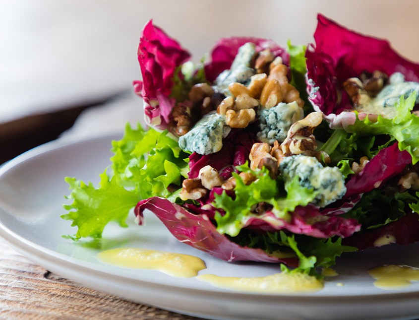 green and purple lettuce topped with walnut and blue cheese crumbles