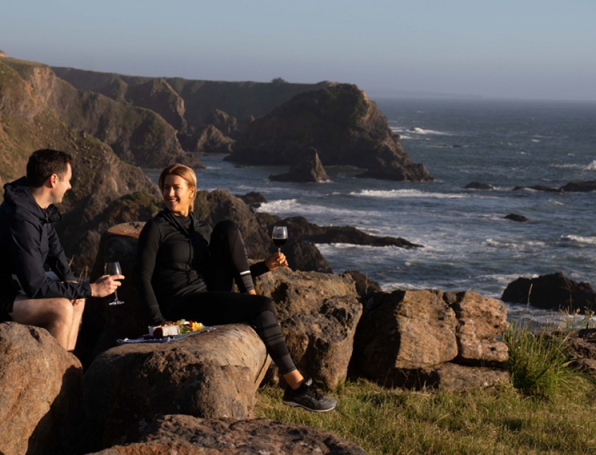couple having a picnic on cliffside over ocean