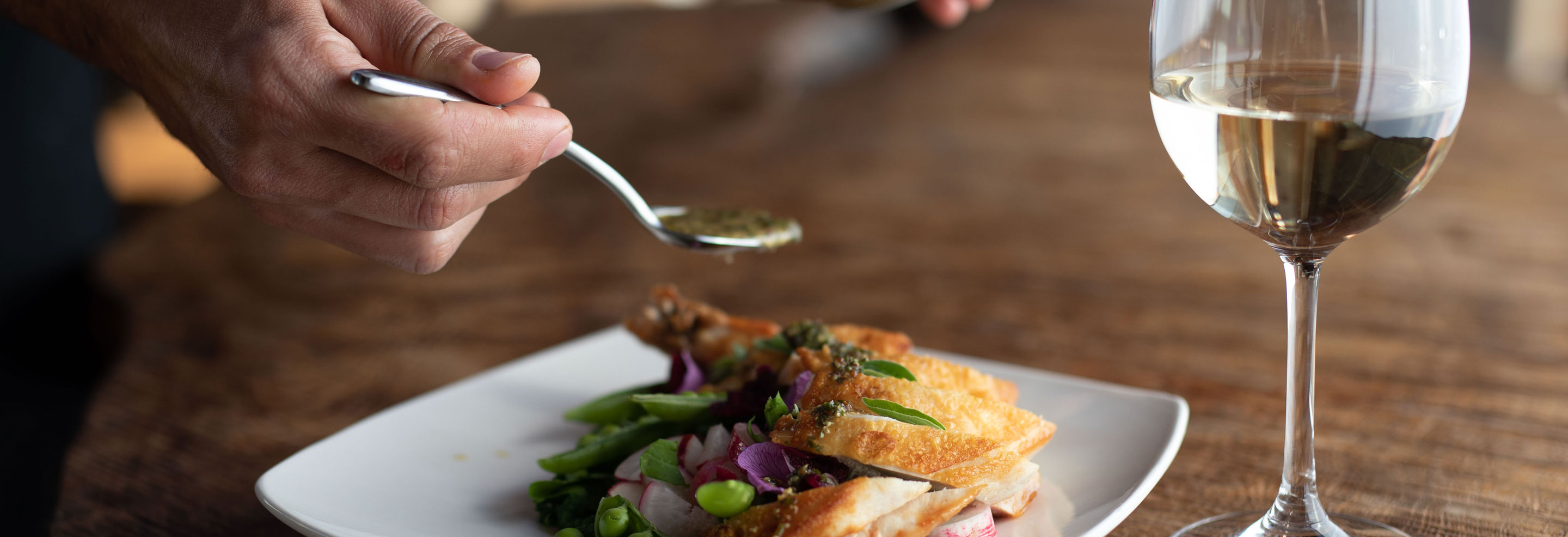 food dish with win and hand holding spoon with sauce