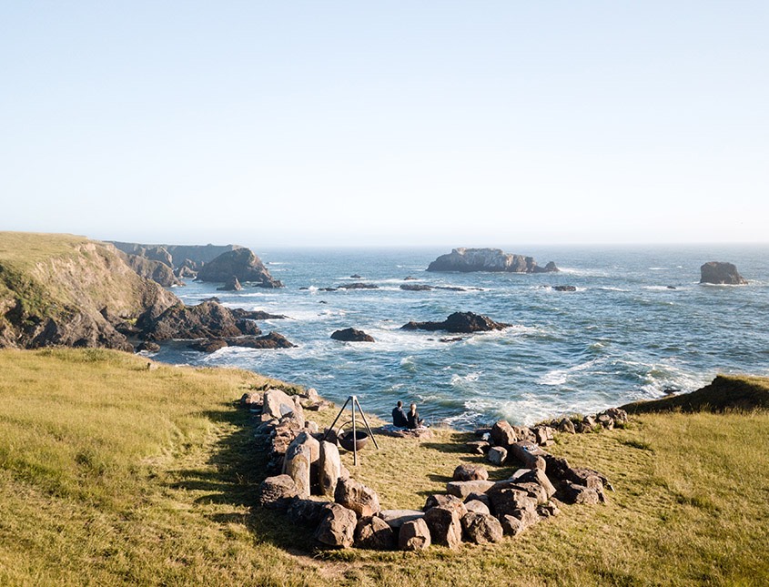 fire pit surrounded by large rocks in a u shape overlooking the ocean