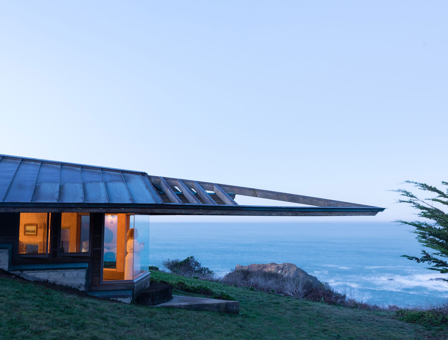 outside view of the room with a woman overlooking the ocean view