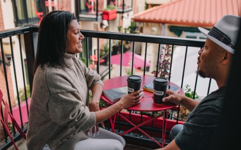 couple drinking coffee at a balcony with red table