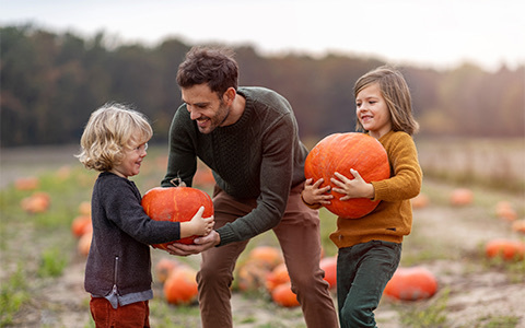 two boys and a man carrying giant pumpkins