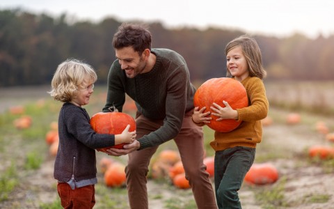 dad giving pumpkins to his daughters