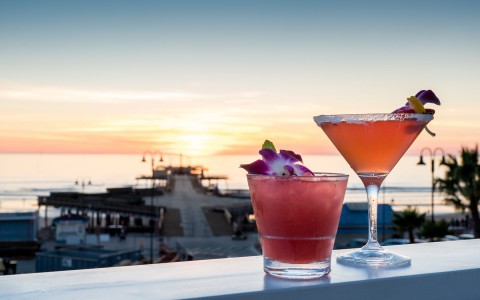 2 craft cocktails with view of pier