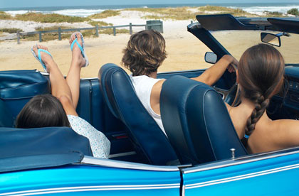 Friends driving in a blue convertible near the beach