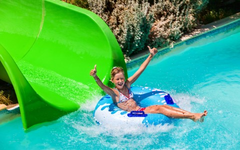 Girl tubing and sliding out of a slide into water