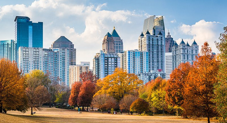 a park in fall with orange and yellow trees with Atlanta skyline in background against blue sky