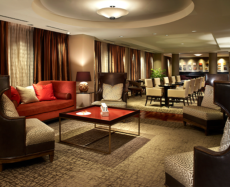  club lounge, warm lighting, red couch and brown and beige comfy chairs 