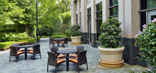 outdoor patio area with brown patio furniture on a grey stone flooring and large planter pots