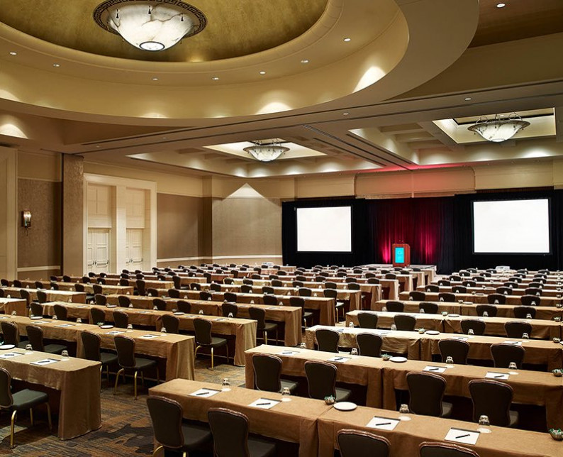 windsor ballroom setup with rows of tables and chairs facing a stage and two screens