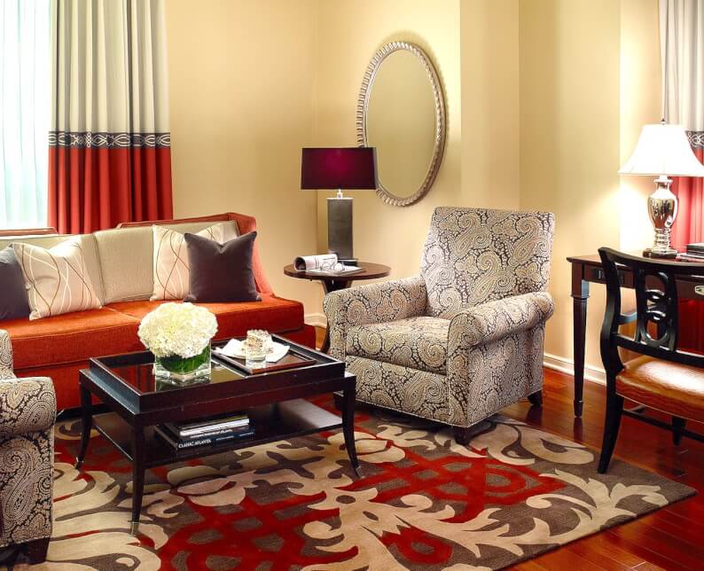 executive suite room seating area with red couch on red rug with console table and lamp