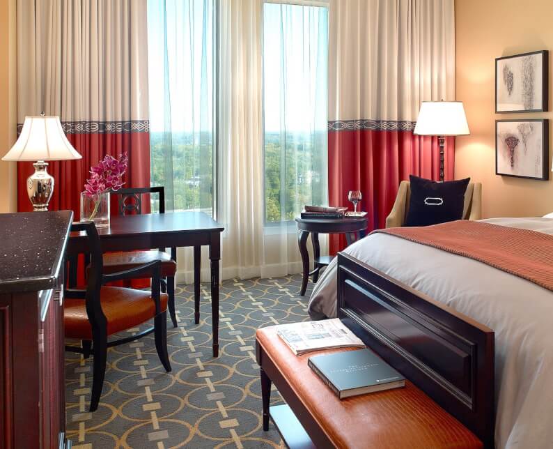 royal room suite with king bed and white and red linens and wood desk with chairs