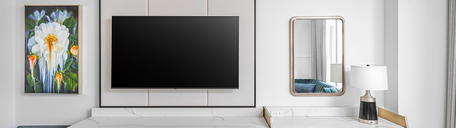 a large flat tv screen with a desk and mirror next to it