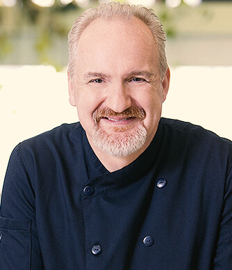 man with grey hair wearing a chef coat