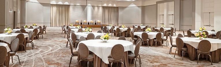large ballroom set with yellow flower arrangements in the center of round tables
