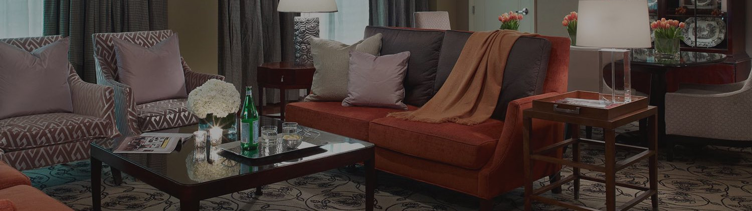 suite room with red couch and chairs in a living area around a wooden table