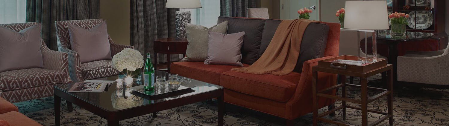 suite room with red couch and chairs in a living area around a wooden table