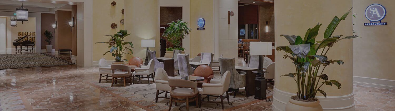 wide view of hotel lobby with columns and high ceilings and chairs and tables