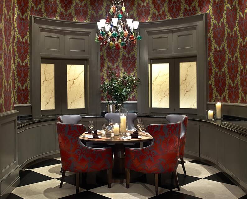 corner dining nook at southern art restaurant with round table and chairs under a multi colored glass chandelier