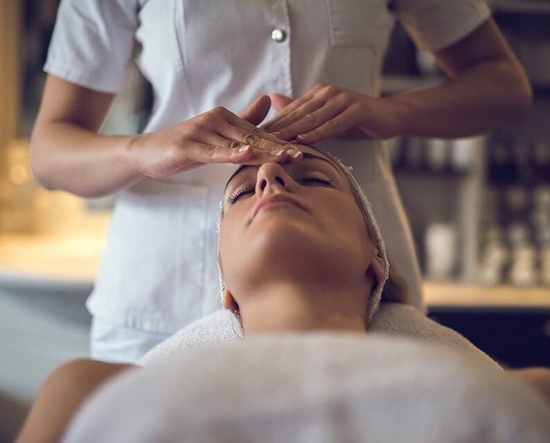 woman receiving a facial treatment at a spa resting on a white towel