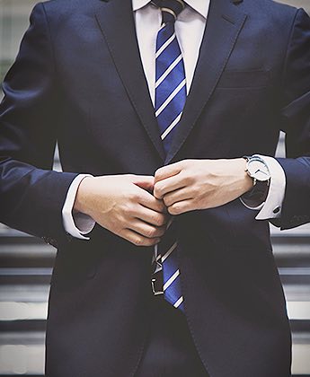 man holding hands wearing a black suit