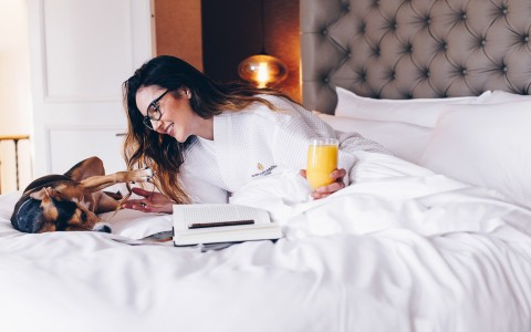 woman playing with her dog drinking orange juice and reading a book