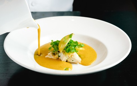 chef pours sauce on some food