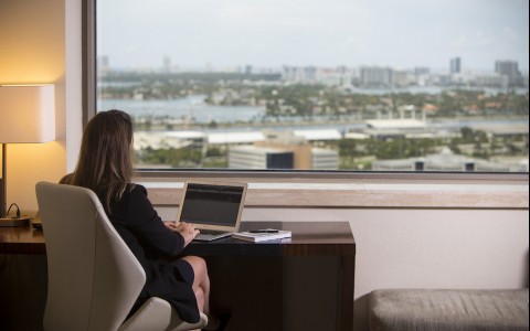 girl woking on her computer looking out the window of a suite