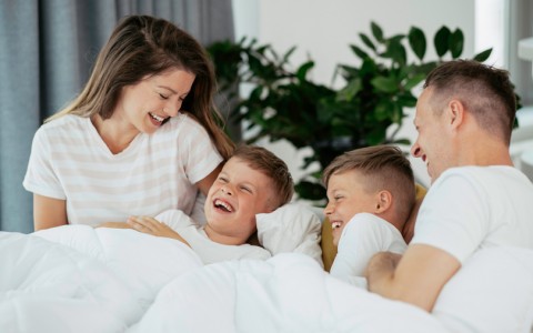 family playing on bed in hotel room