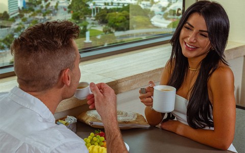 Woman smiling drinking coffee with a man drinking espresso 