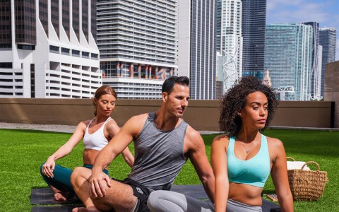 two women and a man stretching on yoga mats out on the terrace