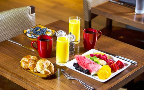 A breakfast layout on the restaurant Ole table. Fruit, croissants, orange juice and coffee